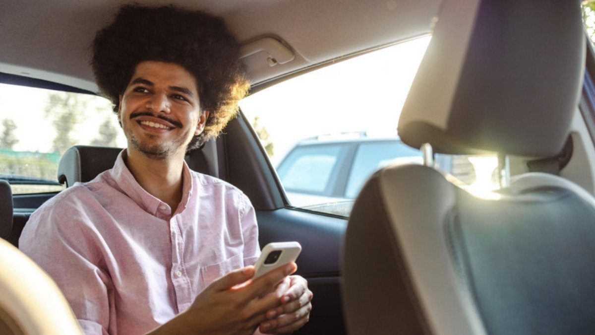 A young man checks his phone from the back seat, the rider's view Uber accident lawyers in Summerville start with after a crash