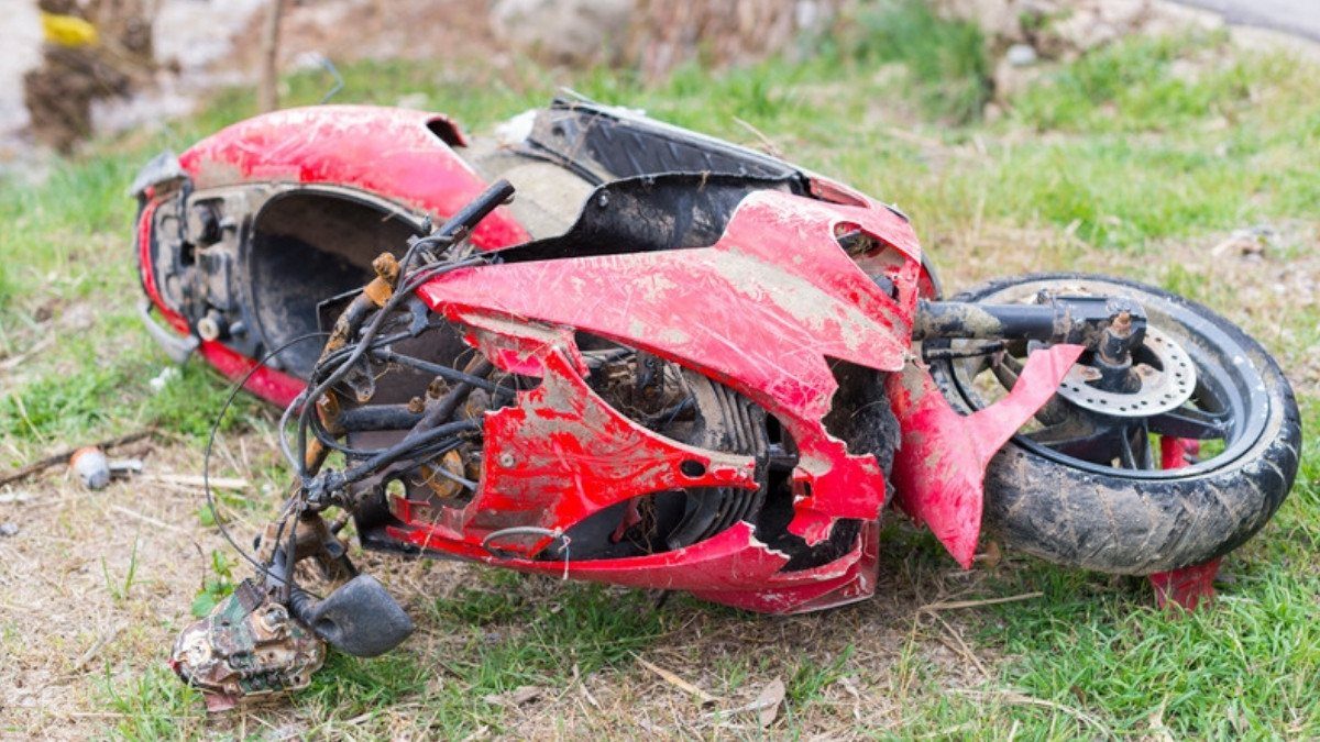 A wrecked red motorcycle lies in roadside grass after a crash, the kind of loss uninsured motorist motorcycle lawyers in Summerville review