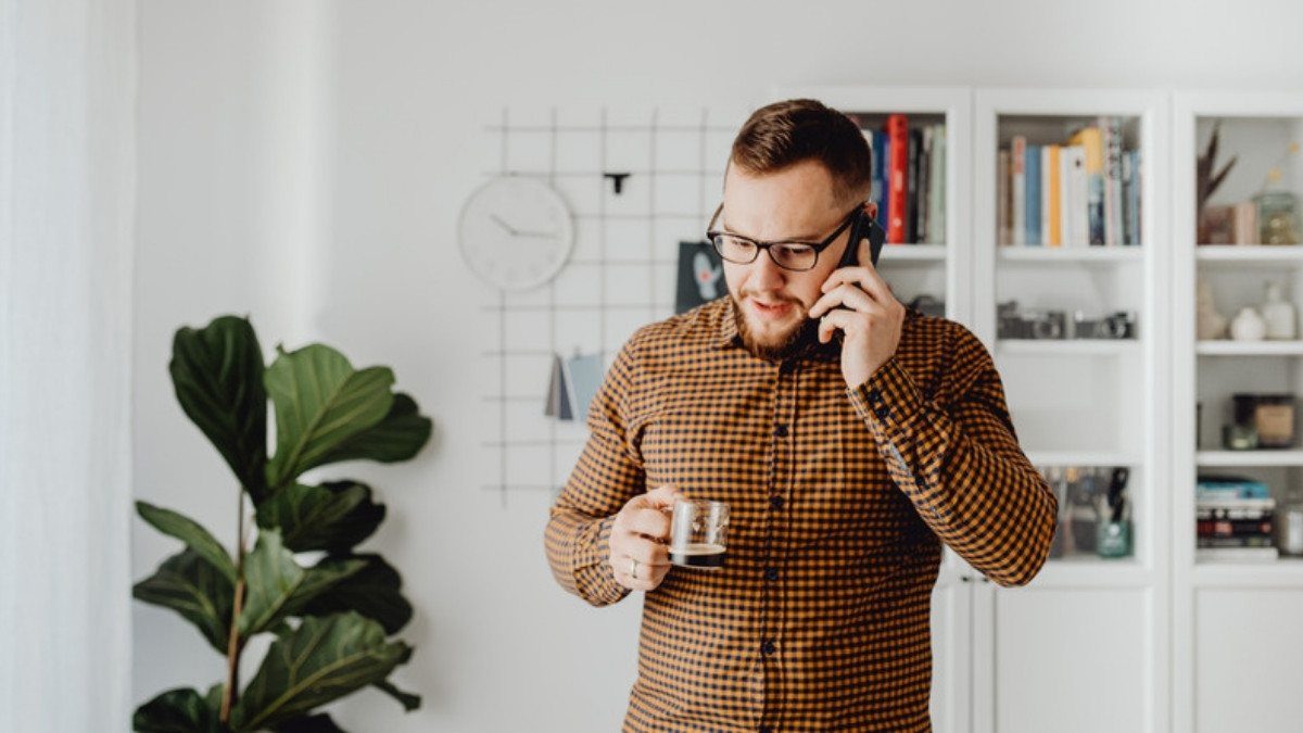 A man holds a coffee cup and talks on the phone at home, working out the next step after a car accident in South Carolina