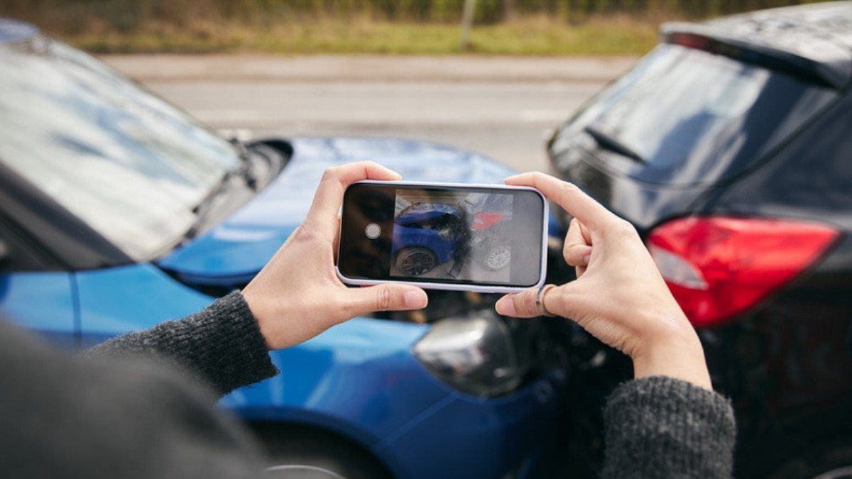 Hands hold up a phone to photograph a rear end crash, one of the first things to do after a car accident in South Carolina