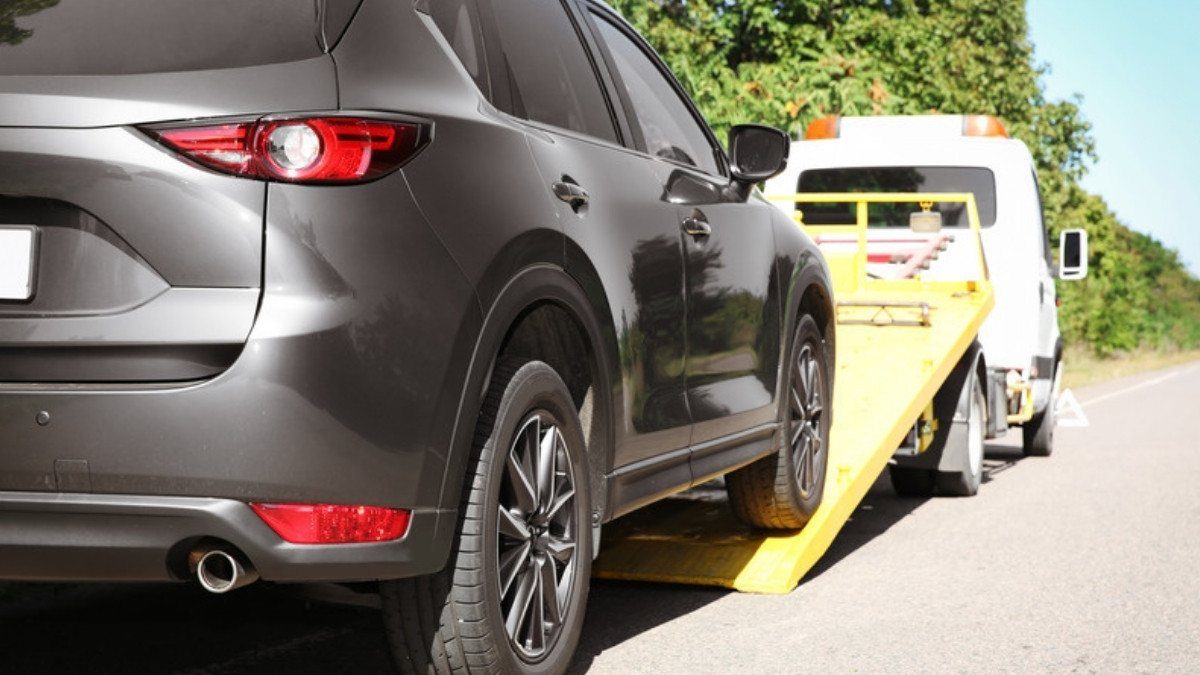 A gray SUV waits to be loaded onto a flatbed tow truck at the roadside, a common sight after a crash that was not your fault