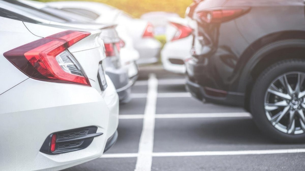 Two cars touch bumpers in a parking lot after a minor car accident, with only light damage showing between them