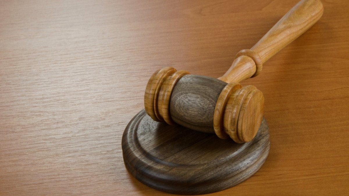 A wooden gavel rests on its round sound block on a polished table, a symbol of the court approval a death settlement needs